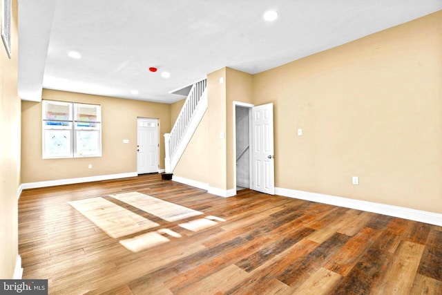 below grade area with stairs, wood finished floors, and baseboards