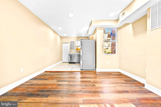 unfurnished living room with baseboards, recessed lighting, and light wood-style flooring