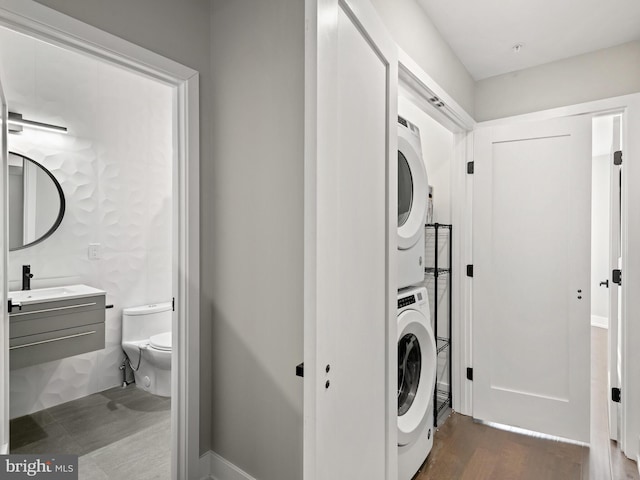 laundry room with stacked washer / drying machine, sink, and dark hardwood / wood-style flooring