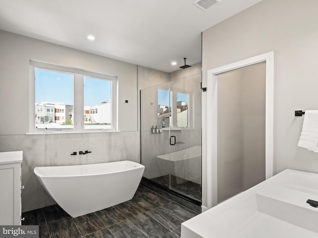 bathroom with vanity, tile walls, and shower with separate bathtub