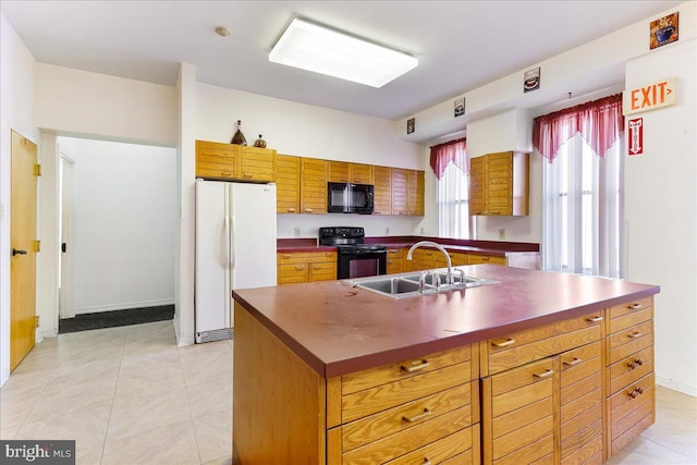 kitchen featuring light tile patterned flooring, black appliances, sink, and a kitchen island with sink