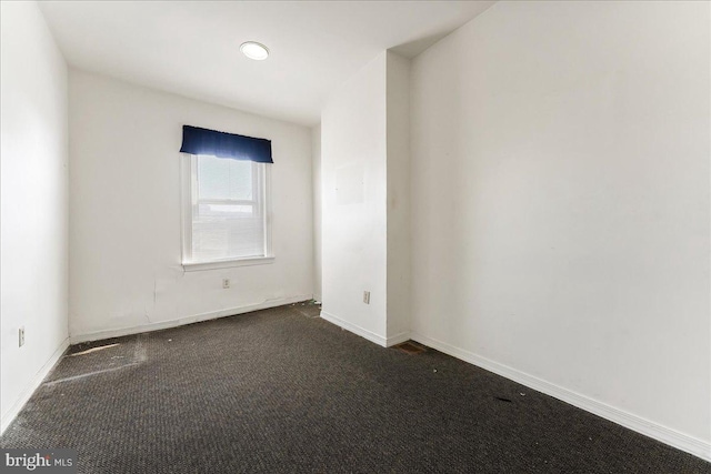 unfurnished room with dark colored carpet