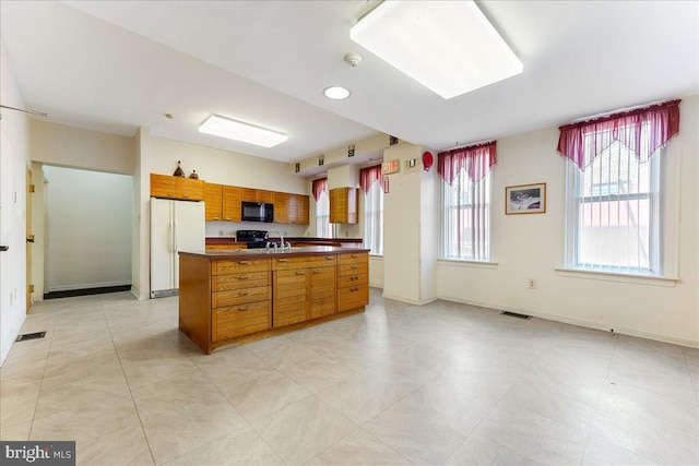 2072 E Clearfield St, Philadelphia, PA 19134 - kitchen featuring brown cabinets, black microwave, visible vents, dark countertops, and freestanding refrigerator