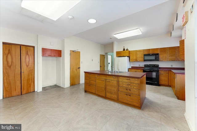 2072 E Clearfield St, Philadelphia, PA 19134 - kitchen featuring brown cabinets, light tile patterned flooring, a center island with sink, black appliances, and dark countertops