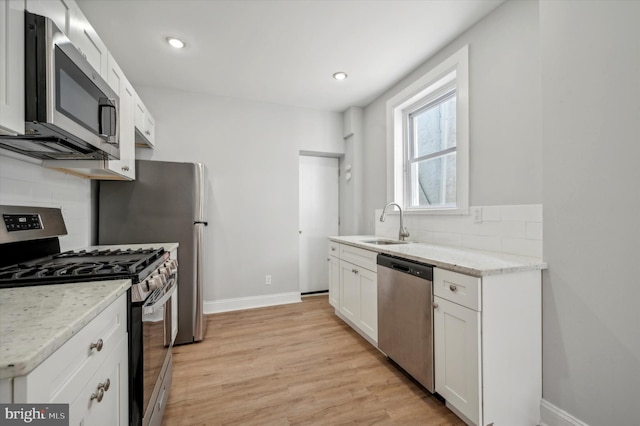 kitchen featuring white cabinetry, stainless steel appliances, tasteful backsplash, and light hardwood / wood-style flooring