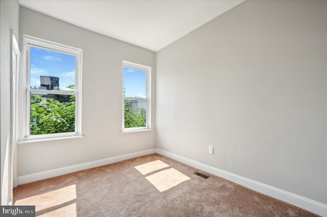 carpeted spare room with vaulted ceiling