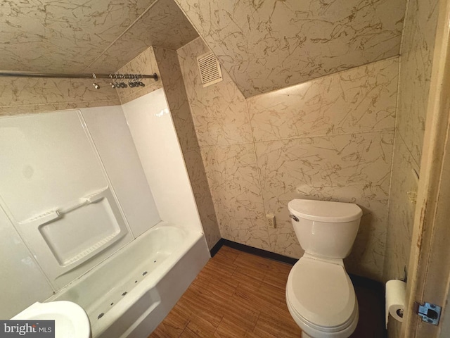 bathroom featuring toilet, wood-type flooring, and  shower combination