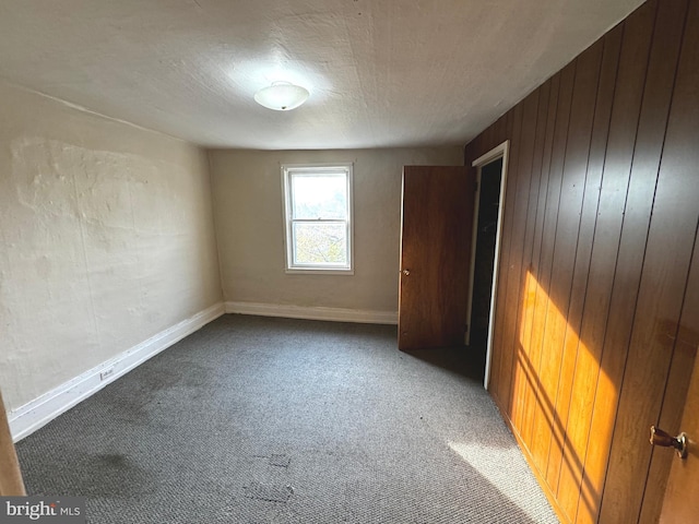 unfurnished bedroom with wood walls and carpet floors