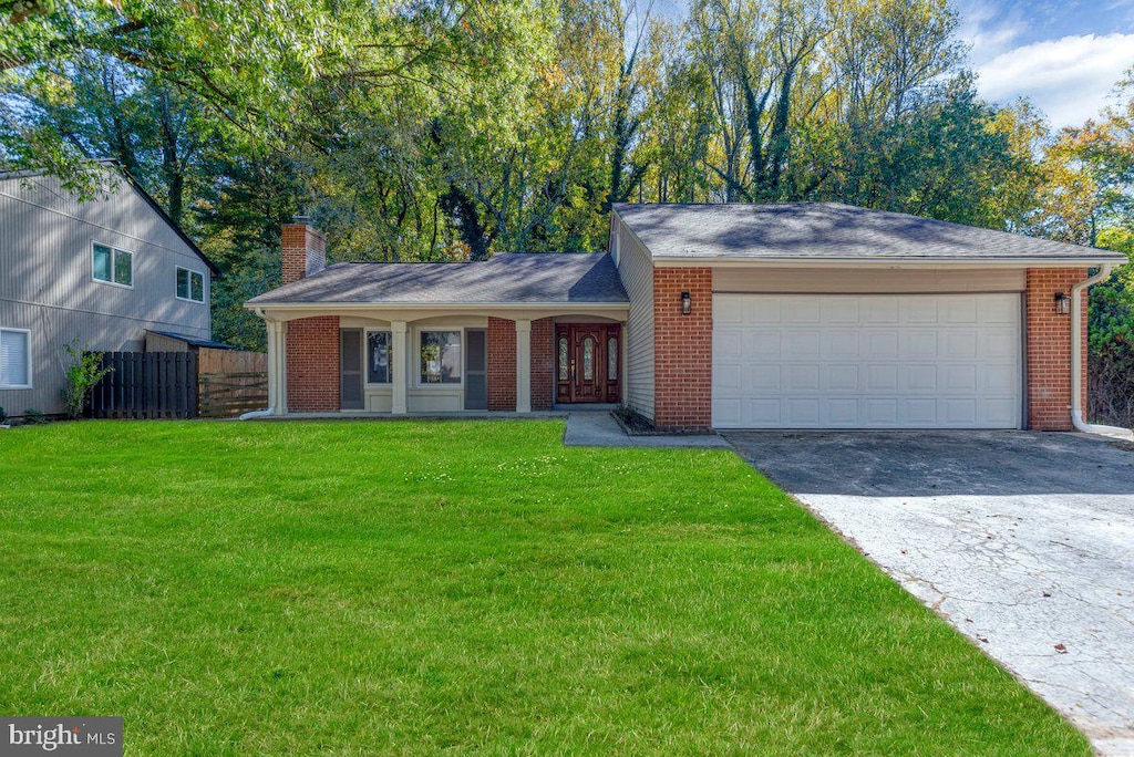 ranch-style house with a chimney, brick siding, fence, aphalt driveway, and a front yard