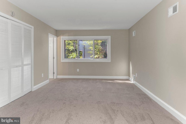 unfurnished bedroom featuring light carpet and a closet