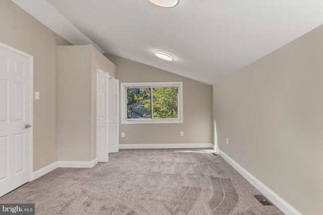 unfurnished bedroom with vaulted ceiling and light colored carpet