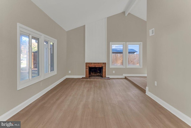 unfurnished living room with beamed ceiling, light hardwood / wood-style flooring, a fireplace, and high vaulted ceiling