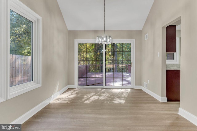 unfurnished dining area with lofted ceiling, light hardwood / wood-style floors, and plenty of natural light