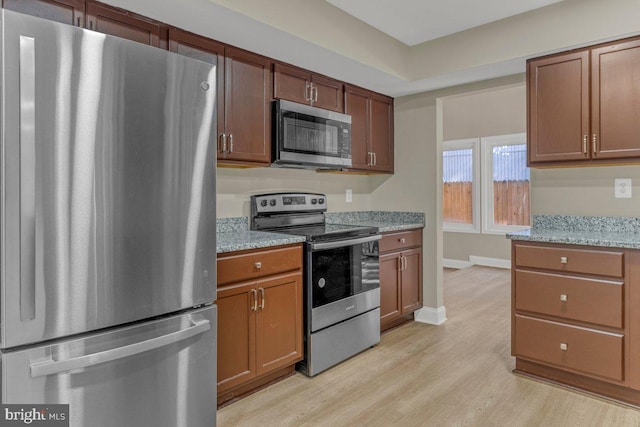 kitchen featuring light stone counters, appliances with stainless steel finishes, and light wood-type flooring