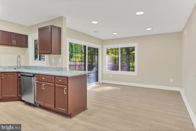 kitchen with stainless steel dishwasher, light hardwood / wood-style flooring, light stone counters, and kitchen peninsula