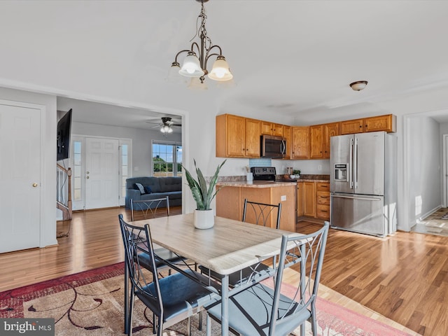 dining area featuring ceiling fan with notable chandelier and light hardwood / wood-style floors