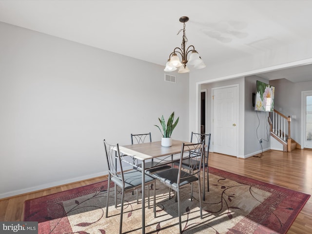 dining area with hardwood / wood-style floors and a chandelier