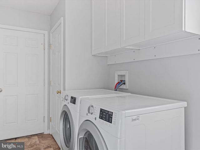 clothes washing area with separate washer and dryer and cabinets