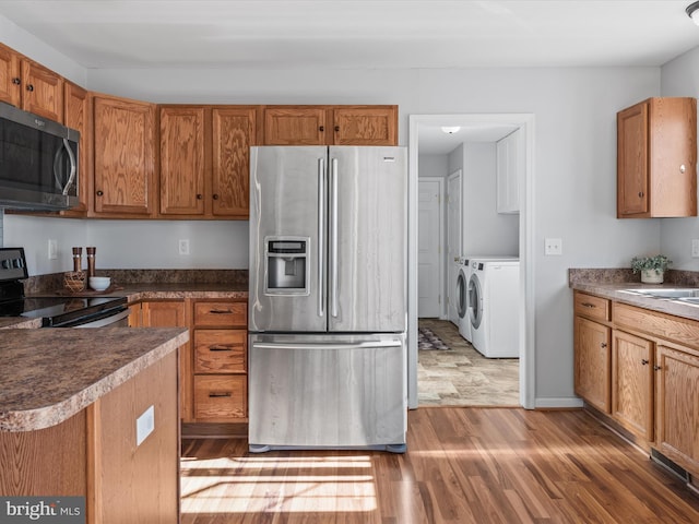 kitchen with stainless steel appliances, separate washer and dryer, and dark hardwood / wood-style flooring