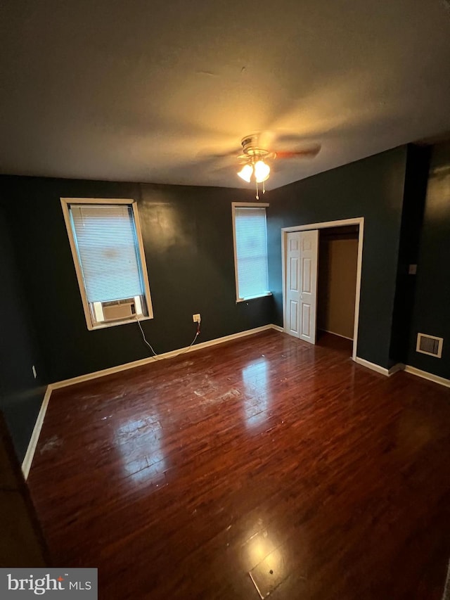 unfurnished bedroom with cooling unit, hardwood / wood-style flooring, a closet, and ceiling fan