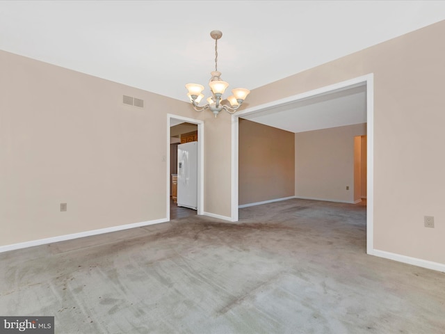 carpeted spare room featuring an inviting chandelier