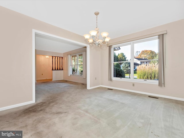 carpeted spare room featuring a notable chandelier and a healthy amount of sunlight