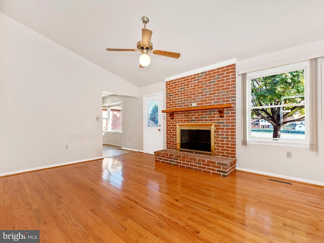 unfurnished living room featuring light hardwood / wood-style floors, ceiling fan, vaulted ceiling, and a brick fireplace