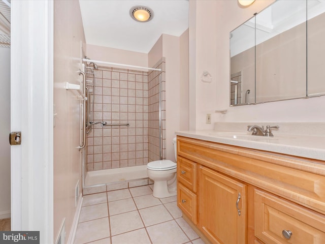 bathroom with vanity, tiled shower, toilet, and tile patterned floors