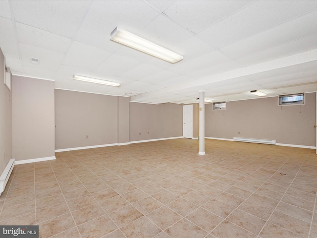 basement with a paneled ceiling and a baseboard radiator