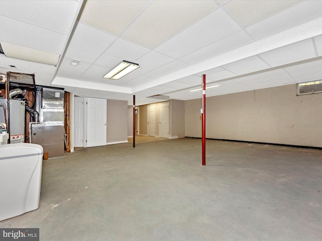 basement with a paneled ceiling, heating unit, and water heater