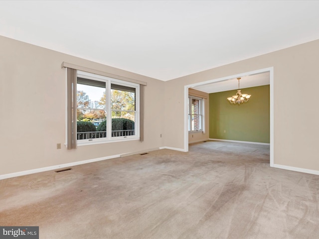 carpeted empty room with a chandelier