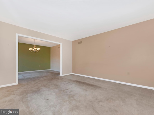 carpeted empty room with a chandelier