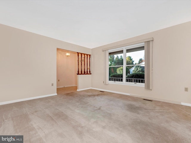 carpeted spare room featuring an inviting chandelier