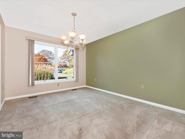 carpeted empty room featuring a chandelier