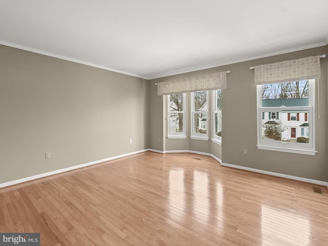 empty room with light hardwood / wood-style floors, crown molding, and plenty of natural light