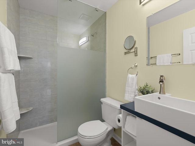 bathroom featuring vanity, toilet, and a tile shower