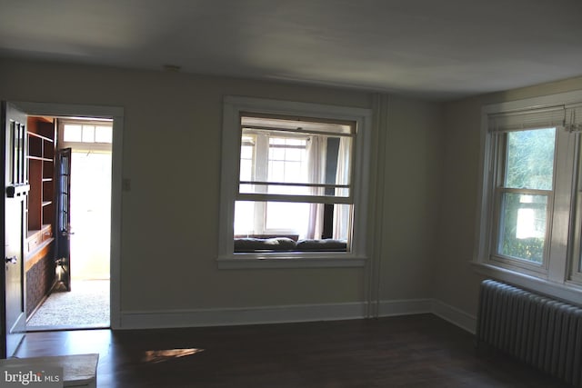 empty room featuring dark hardwood / wood-style floors and radiator heating unit