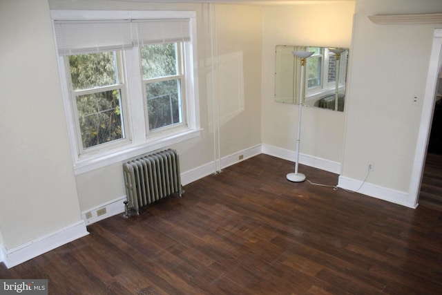 unfurnished room with dark hardwood / wood-style flooring and radiator heating unit