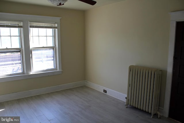 unfurnished room featuring ceiling fan, a healthy amount of sunlight, light wood-type flooring, and radiator