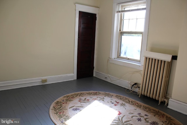 unfurnished room with radiator heating unit and dark wood-type flooring