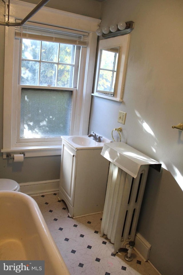 bathroom with radiator, vanity, and toilet