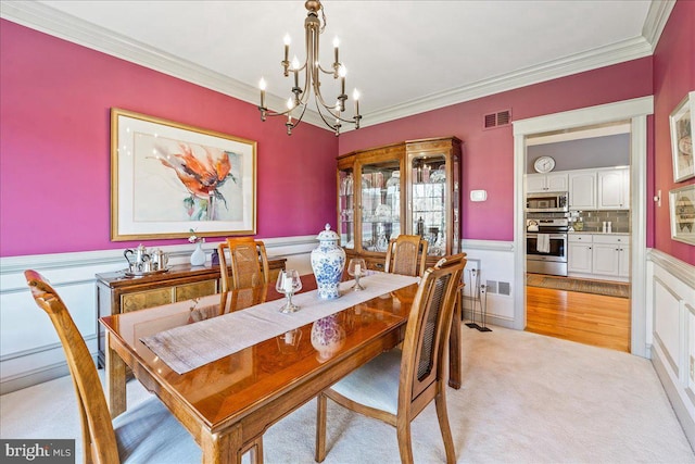 dining room featuring an inviting chandelier, light wood-type flooring, and ornamental molding