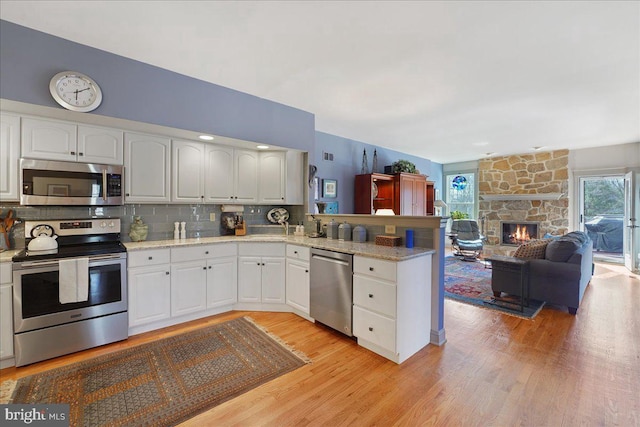 kitchen featuring white cabinets, a healthy amount of sunlight, kitchen peninsula, and appliances with stainless steel finishes