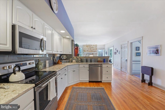 kitchen featuring white cabinets, light wood-type flooring, and appliances with stainless steel finishes