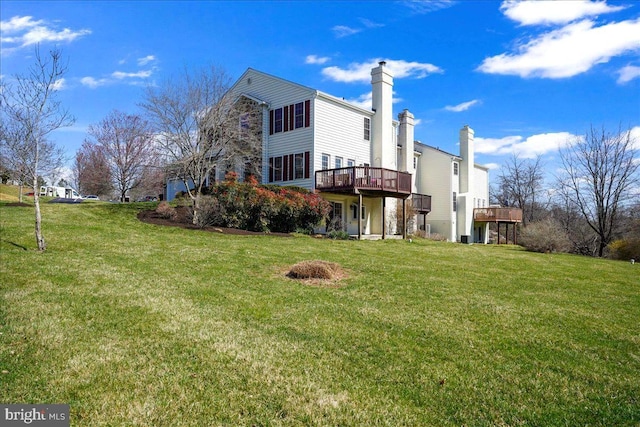 rear view of property featuring a lawn and a deck