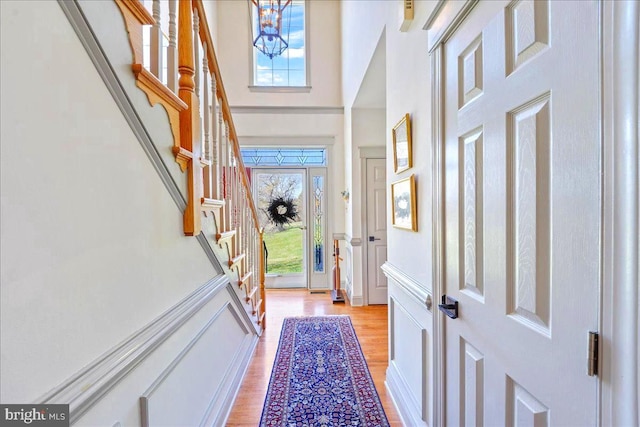 foyer featuring a high ceiling, light hardwood / wood-style flooring, plenty of natural light, and a notable chandelier