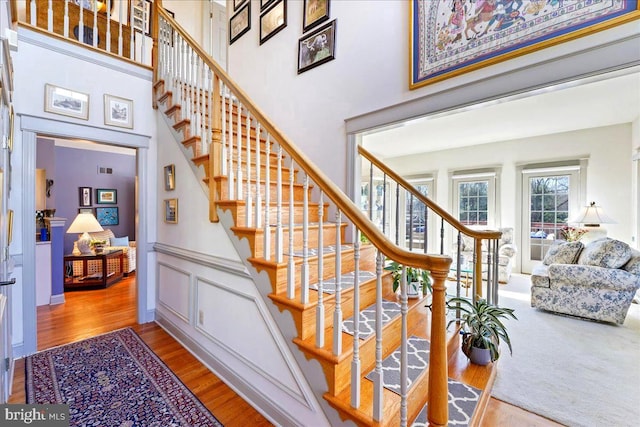 stairs featuring hardwood / wood-style flooring and a towering ceiling