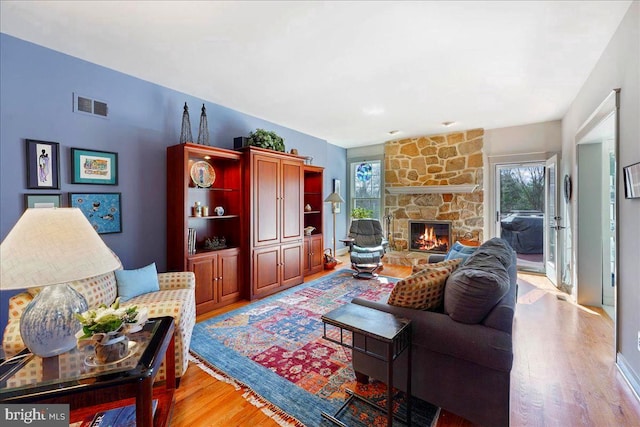 living room featuring light wood-type flooring and a stone fireplace