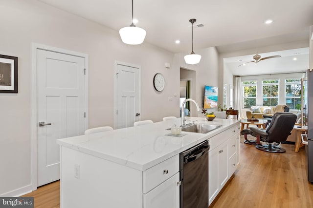 kitchen featuring pendant lighting, ceiling fan, black dishwasher, and an island with sink