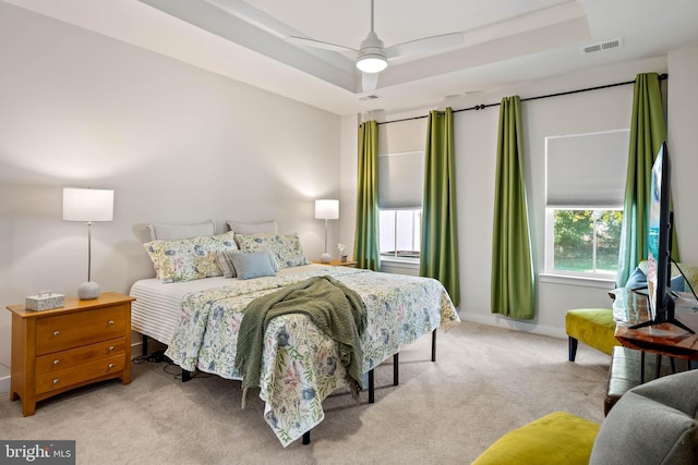 carpeted bedroom featuring ceiling fan and a tray ceiling